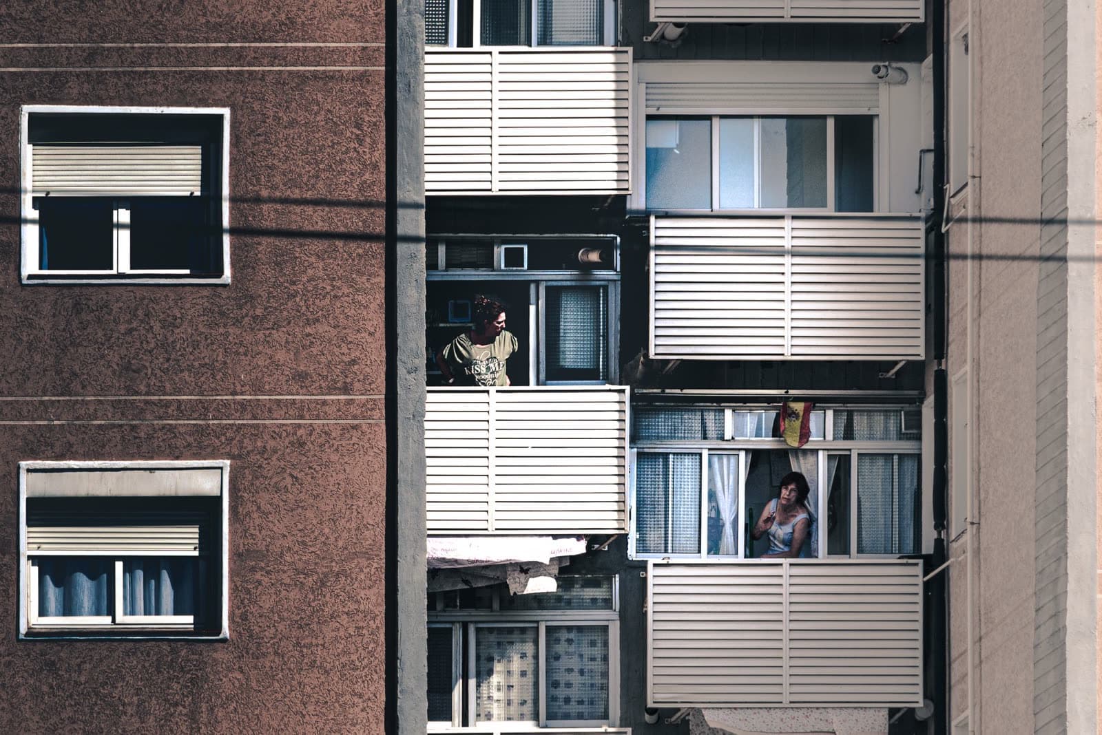 Bloque de viviendas con persianas enrollables blancas bajadas y balcones con celosía