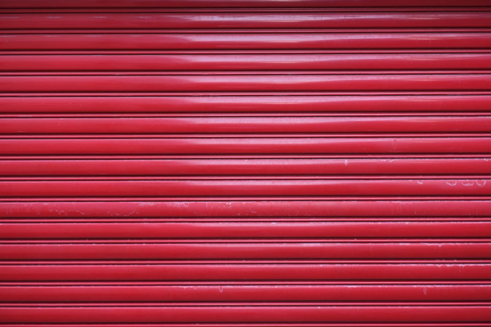 Persiana enrollable metálica de color rojo vista de cerca, con las lamas cerradas