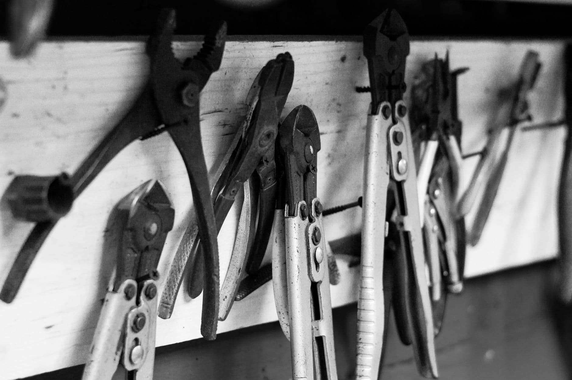 Herramientas de mano colgadas en un panel de taller, en blanco y negro