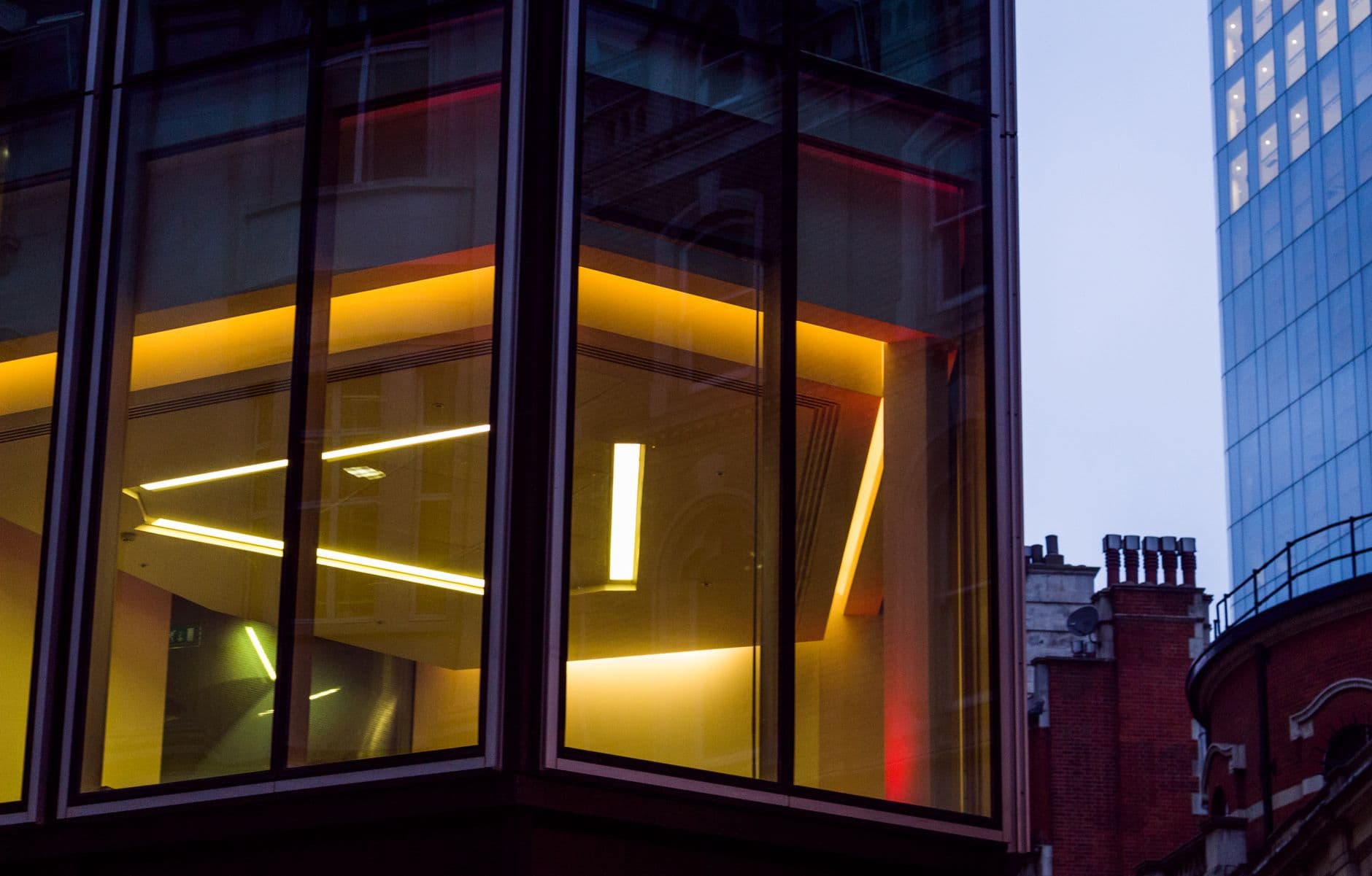 Esquina acristalada de un edificio de oficinas iluminada al anochecer