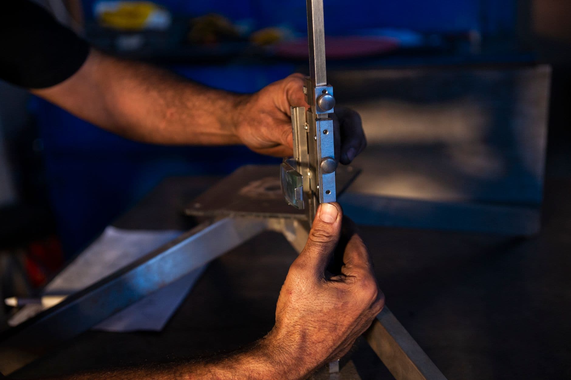 Manos midiendo un perfil metálico con un pie de rey en un taller