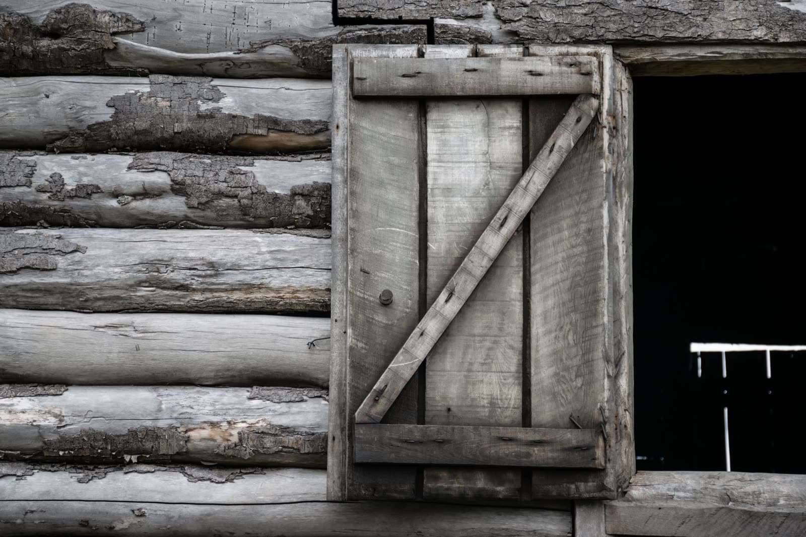Contraventana de tablas envejecida en una pared de troncos