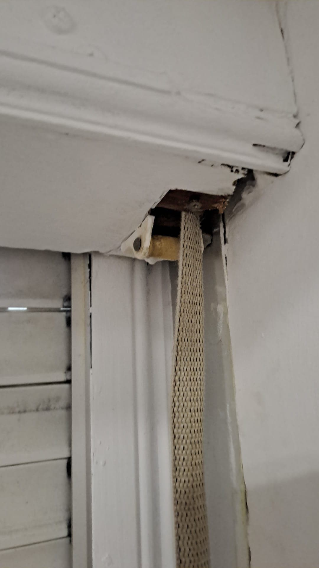 Registro superior del cajón abierto en el interior de una vivienda, con la cinta nueva de color crudo pasada y el soporte blanco del rodillo a la vista